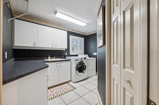 washroom with washer and clothes dryer, cabinets, sink, a textured ceiling, and light tile patterned flooring