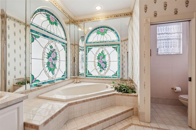 bathroom with vanity, tile patterned floors, toilet, a wealth of natural light, and tiled bath