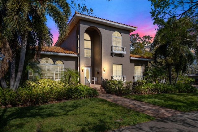 mediterranean / spanish home featuring a balcony and a yard