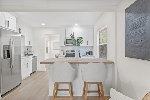 kitchen with a breakfast bar, white cabinetry, tasteful backsplash, and appliances with stainless steel finishes