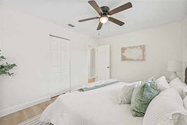 bedroom with ceiling fan, light hardwood / wood-style flooring, and a closet