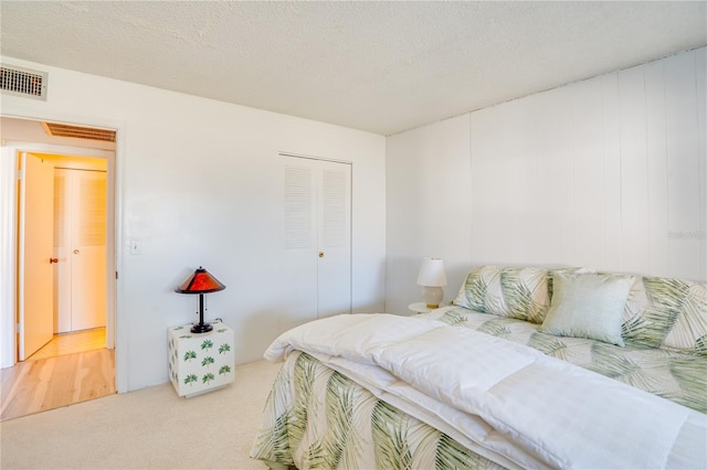 carpeted bedroom with a textured ceiling and a closet