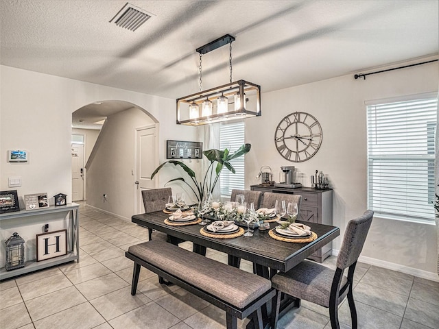 tiled dining space featuring a textured ceiling and a healthy amount of sunlight