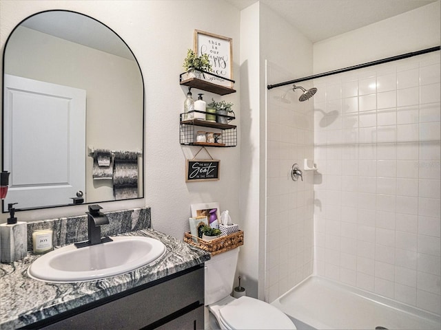 bathroom with vanity, toilet, and a tile shower