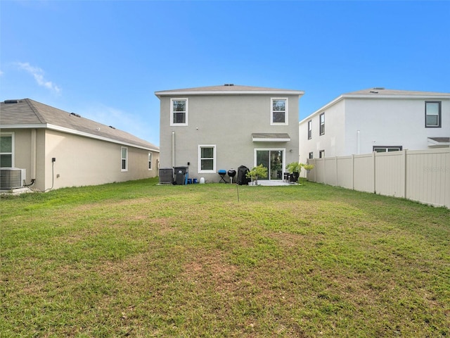 rear view of property featuring a lawn and central air condition unit