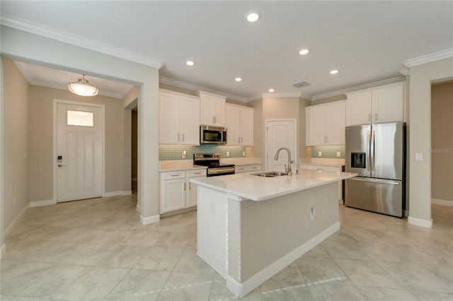 kitchen with decorative backsplash, stainless steel appliances, sink, white cabinetry, and an island with sink