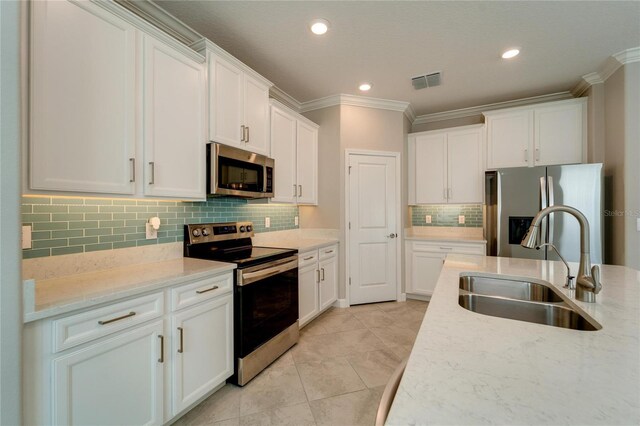 kitchen with sink, decorative backsplash, light stone countertops, appliances with stainless steel finishes, and white cabinetry