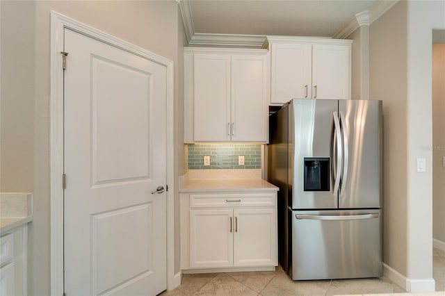 kitchen with stainless steel fridge with ice dispenser, light tile patterned flooring, decorative backsplash, white cabinets, and ornamental molding