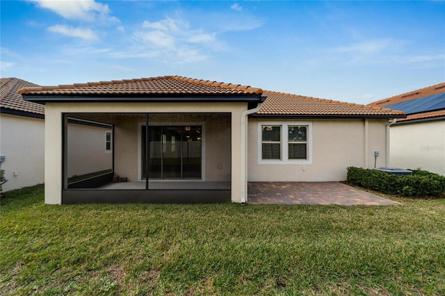 rear view of house with a sunroom, a yard, and a patio