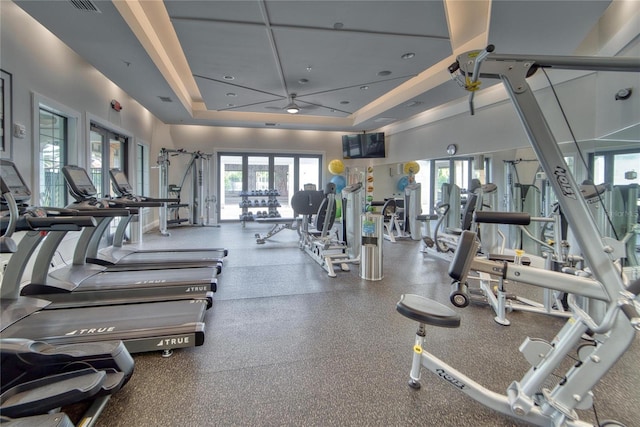 workout area with ceiling fan, a raised ceiling, a high ceiling, and french doors