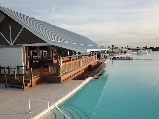 view of pool featuring a water view and a patio