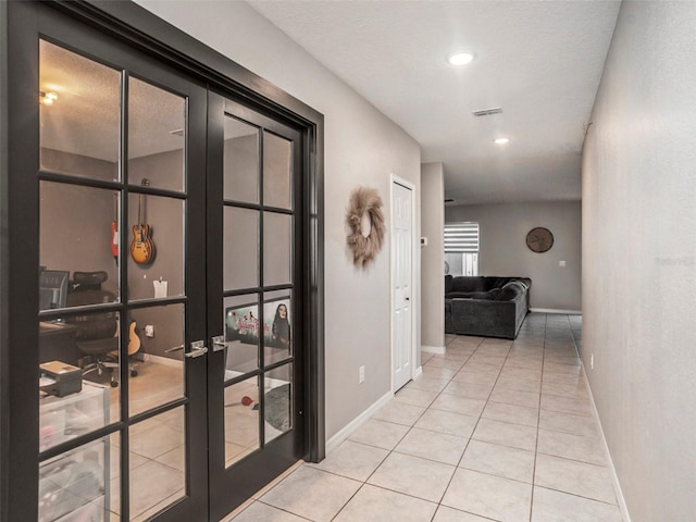 hallway with french doors, a textured ceiling, and light tile patterned floors