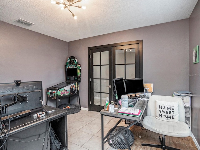 tiled home office with a notable chandelier, a textured ceiling, and french doors