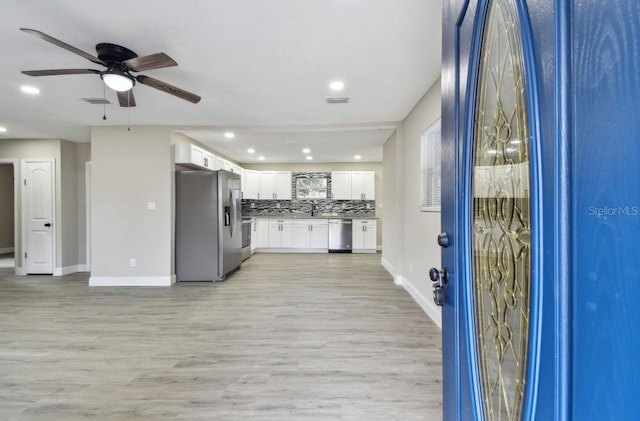 kitchen with ceiling fan, light wood-type flooring, tasteful backsplash, white cabinetry, and stainless steel appliances