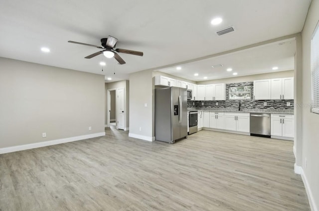 kitchen with ceiling fan, appliances with stainless steel finishes, decorative backsplash, white cabinets, and light wood-type flooring