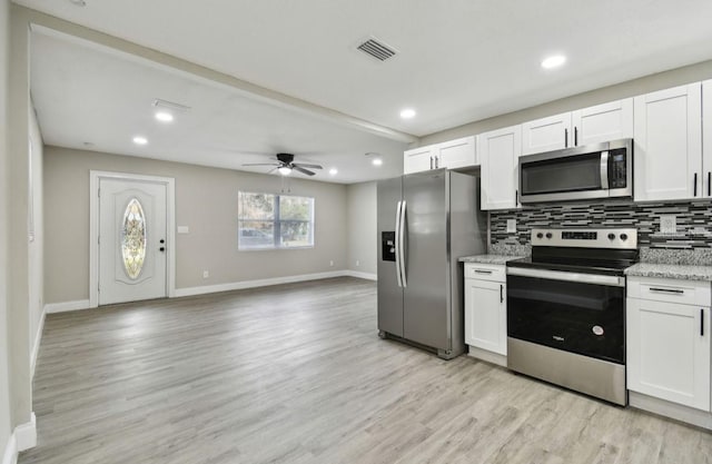 kitchen featuring decorative backsplash, stainless steel appliances, white cabinetry, and light stone counters