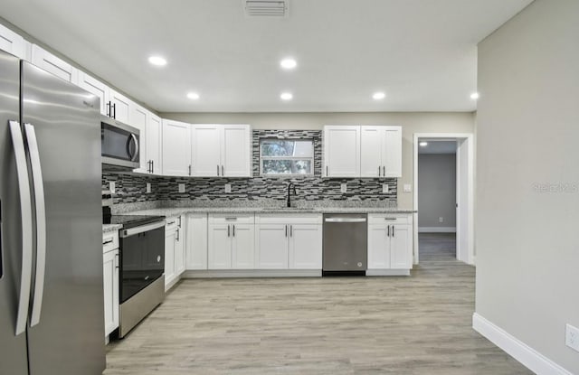 kitchen featuring white cabinetry, light stone counters, and stainless steel appliances