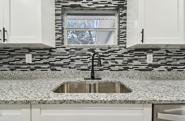 kitchen featuring decorative backsplash, white cabinetry, sink, and light stone counters