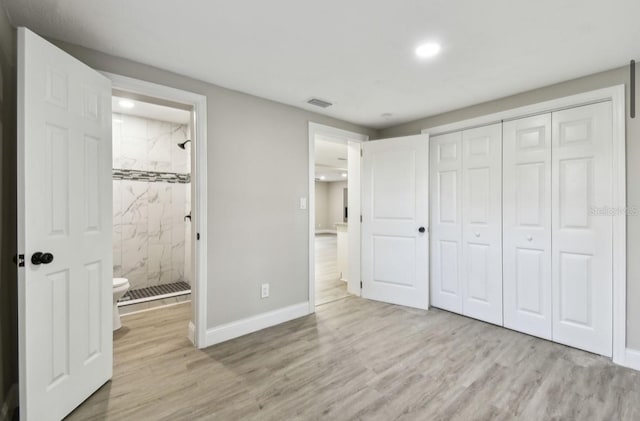 unfurnished bedroom featuring ensuite bath, a closet, and light hardwood / wood-style floors