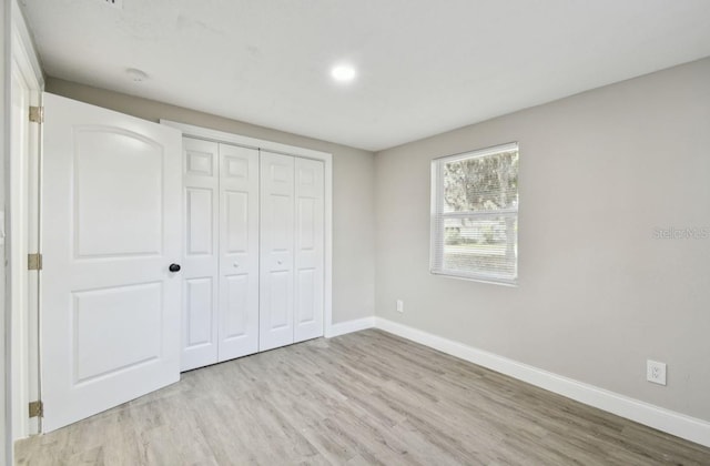 unfurnished bedroom with light wood-type flooring and a closet