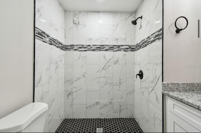 bathroom featuring a tile shower, vanity, and toilet