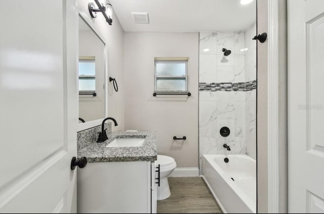 full bathroom featuring vanity, tiled shower / bath combo, a healthy amount of sunlight, hardwood / wood-style flooring, and toilet