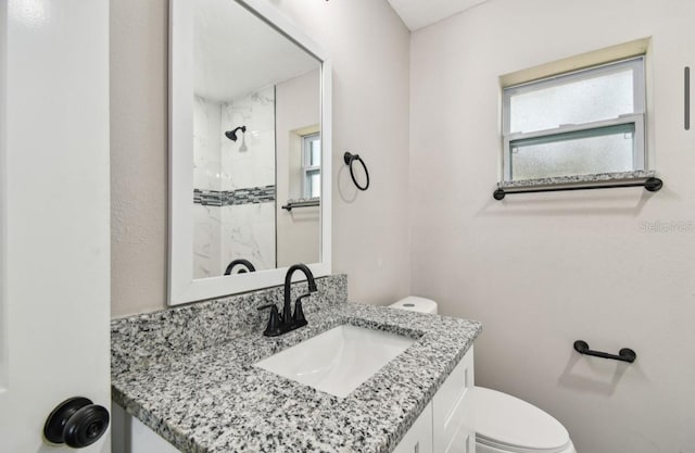 bathroom featuring vanity, toilet, and a tile shower