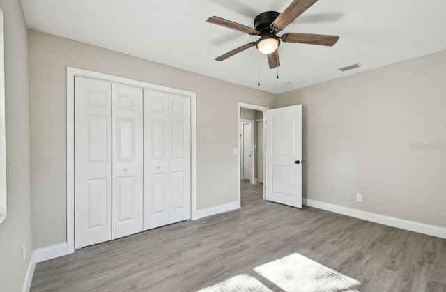 unfurnished bedroom featuring ceiling fan, a closet, and light wood-type flooring