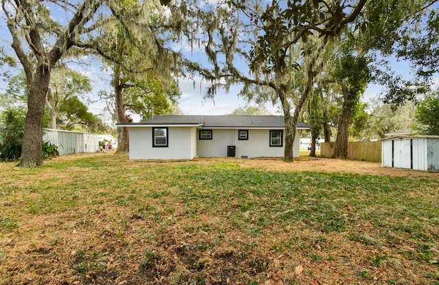 rear view of property with a yard and a storage shed