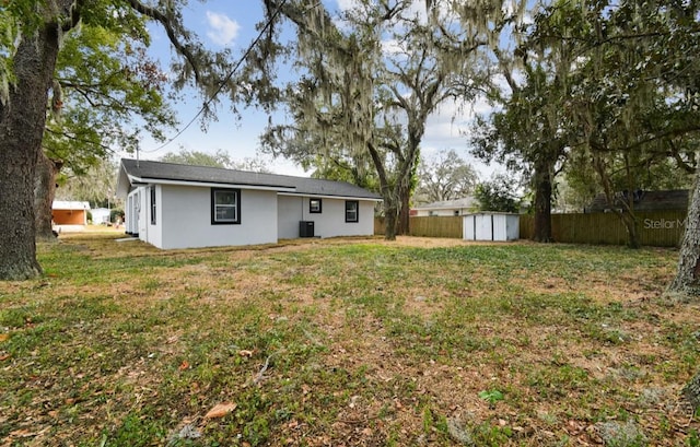 rear view of house with a lawn, a storage shed, and central AC