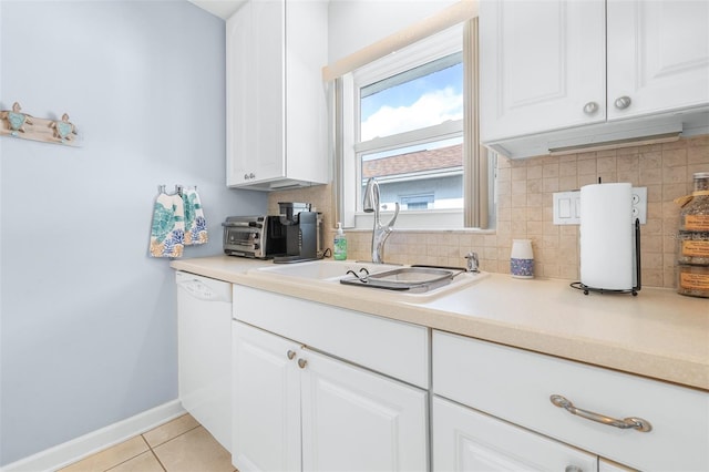 kitchen featuring sink, white dishwasher, white cabinets, light tile patterned flooring, and decorative backsplash