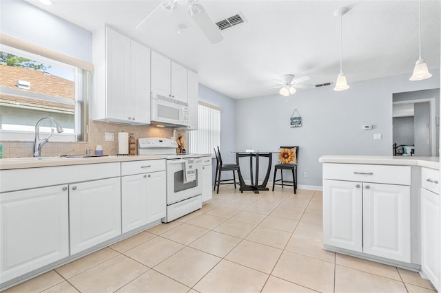 kitchen with a healthy amount of sunlight, white appliances, decorative light fixtures, and white cabinets