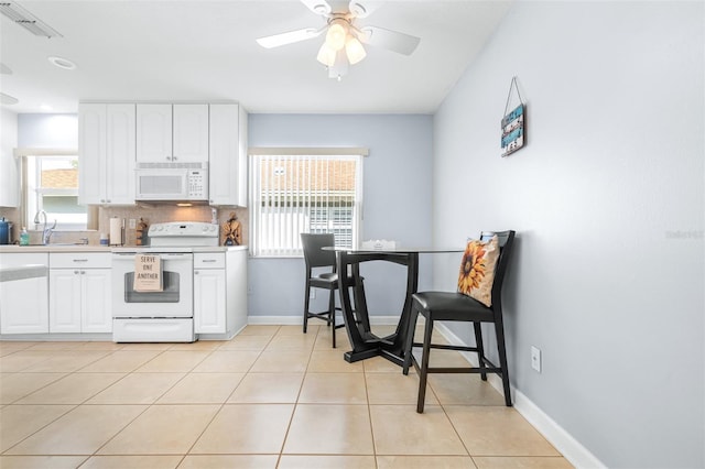 kitchen with a healthy amount of sunlight, light tile patterned floors, white cabinets, and white appliances