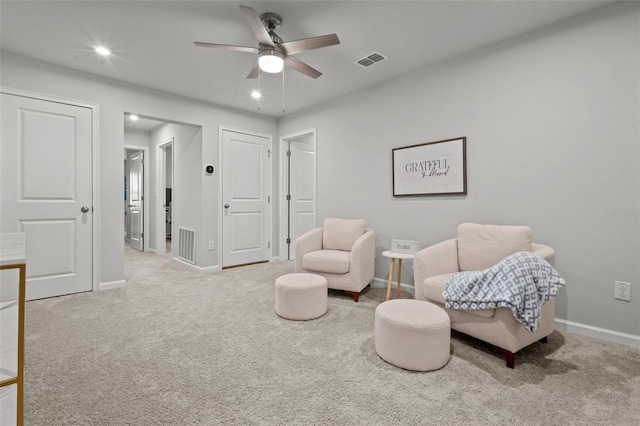 living area featuring light colored carpet and ceiling fan