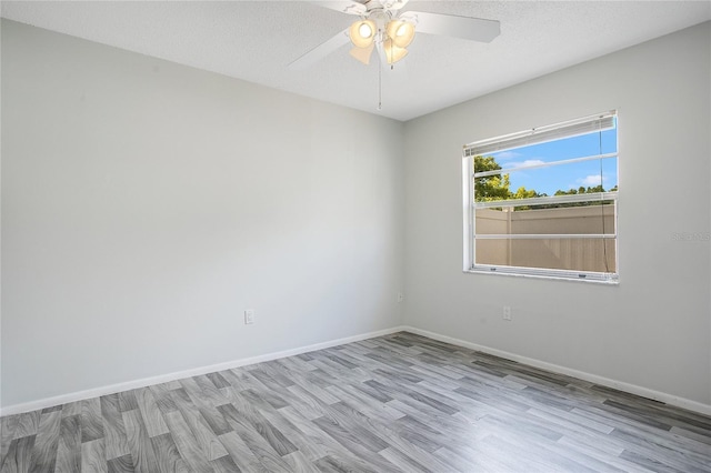 empty room with ceiling fan, light hardwood / wood-style floors, and a textured ceiling