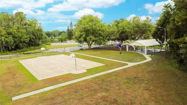 view of home's community with basketball hoop, a lawn, and a playground