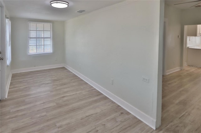 spare room featuring ceiling fan, light wood-type flooring, and crown molding