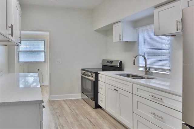 kitchen with white cabinets, sink, stainless steel appliances, and light hardwood / wood-style flooring