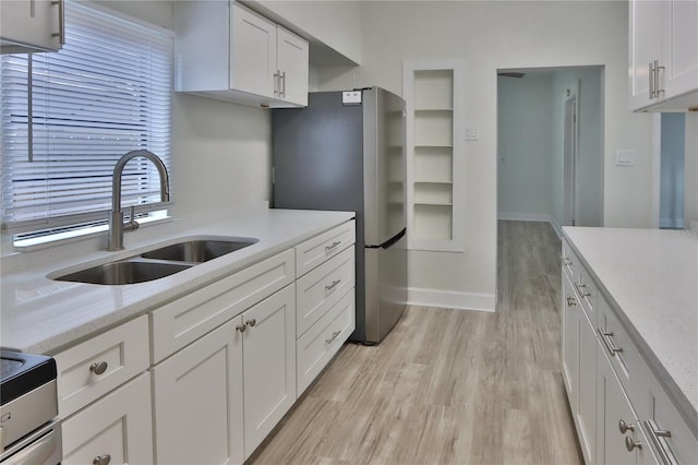 kitchen featuring light hardwood / wood-style floors, white cabinetry, stainless steel refrigerator, and sink