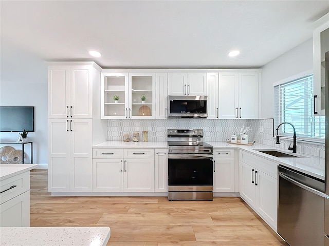 kitchen featuring sink, decorative backsplash, light hardwood / wood-style floors, white cabinetry, and stainless steel appliances