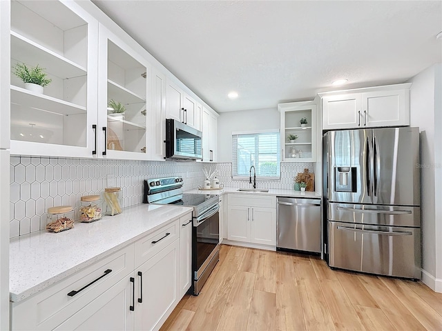 kitchen featuring sink, light stone counters, decorative backsplash, white cabinets, and appliances with stainless steel finishes