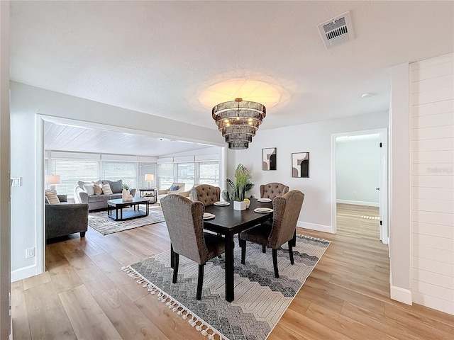 dining area with light wood-type flooring and an inviting chandelier