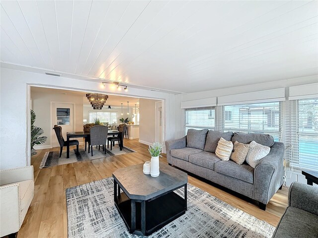 living room featuring hardwood / wood-style floors, an inviting chandelier, and wooden ceiling