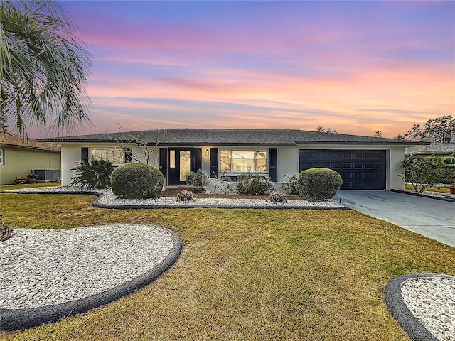 ranch-style house featuring central AC, a garage, and a lawn