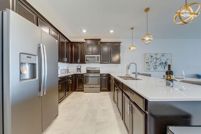 kitchen featuring decorative light fixtures, dark brown cabinetry, stainless steel appliances, and sink