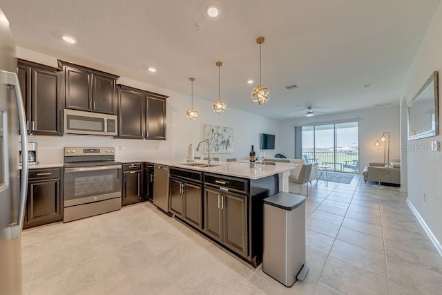 kitchen with hanging light fixtures, sink, ceiling fan, appliances with stainless steel finishes, and kitchen peninsula