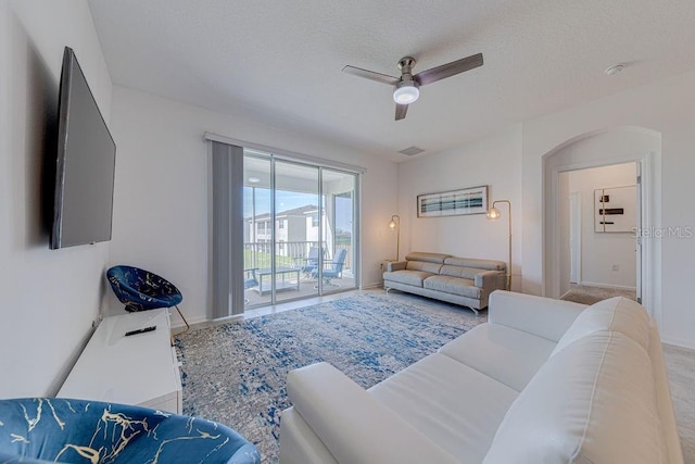 living room featuring ceiling fan and a textured ceiling