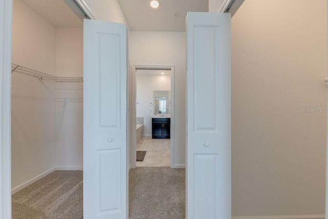 walk in closet with light carpet