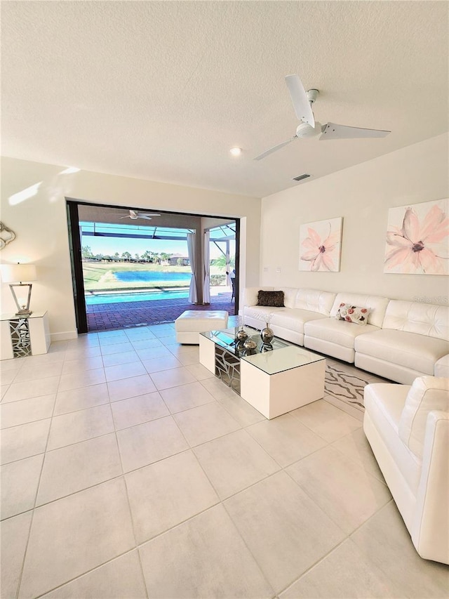 unfurnished living room with light tile patterned flooring, ceiling fan, and a textured ceiling