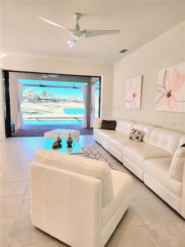 tiled living room with ceiling fan and a textured ceiling